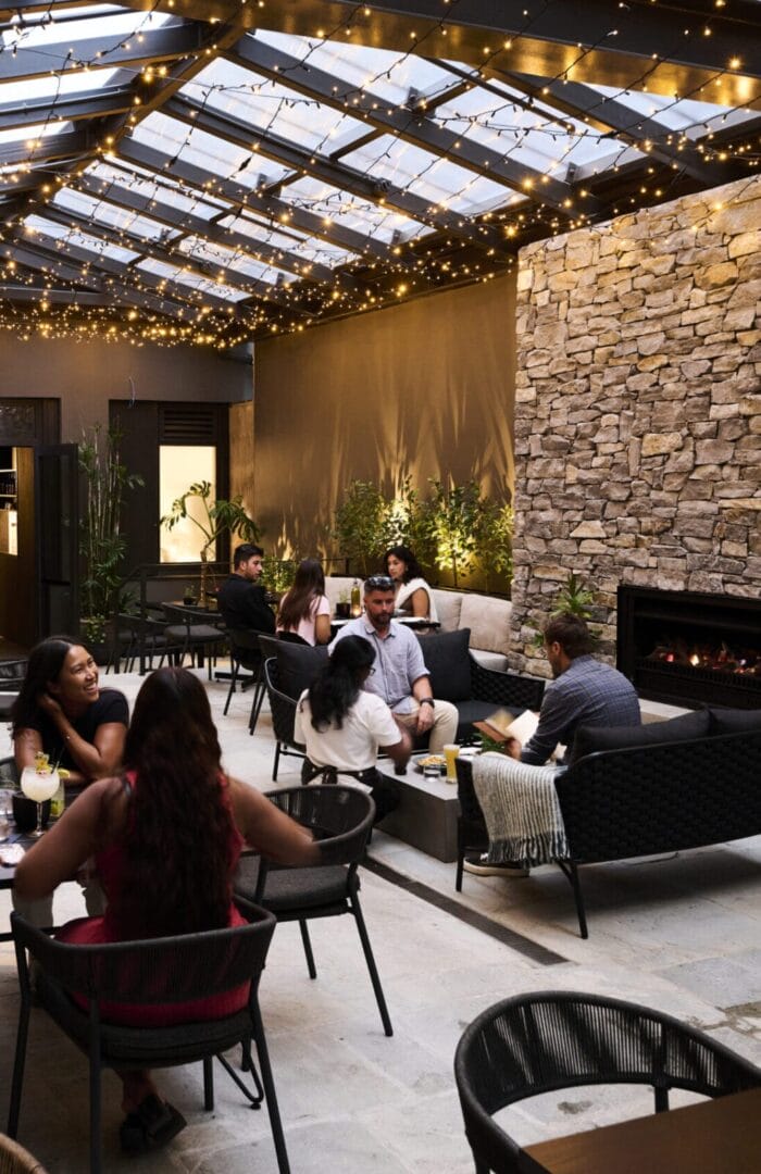 Guests enjoying drinks and conversations at a cozy courtyard lounge with fairy lights.