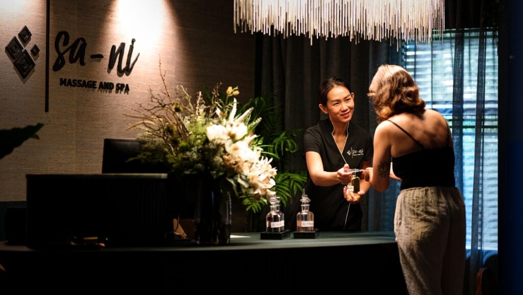Welcoming service at Sa-Ni Massage and Spa, where a friendly staff member greets a guest at the elegant reception desk.