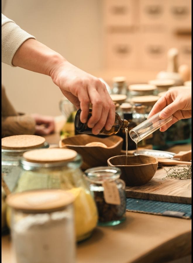 All Zen (1) Hands blending essential oils and natural ingredients in a wellness or apothecary workshop.